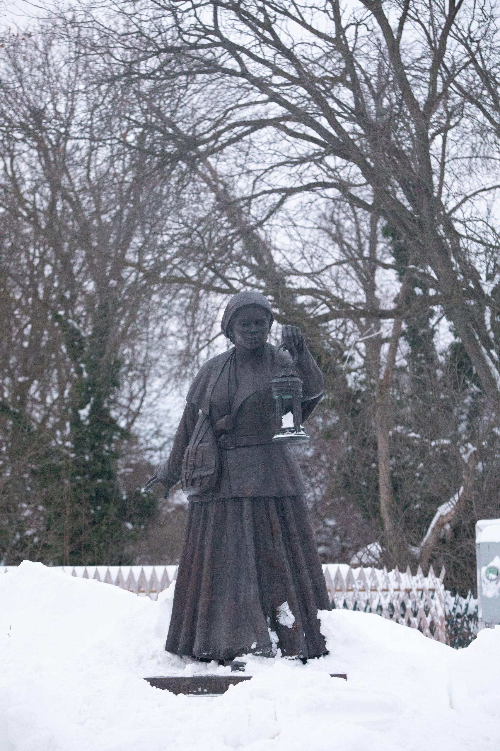 Bronze statue of Harriet Tubman surrounded by snow and bare trees 